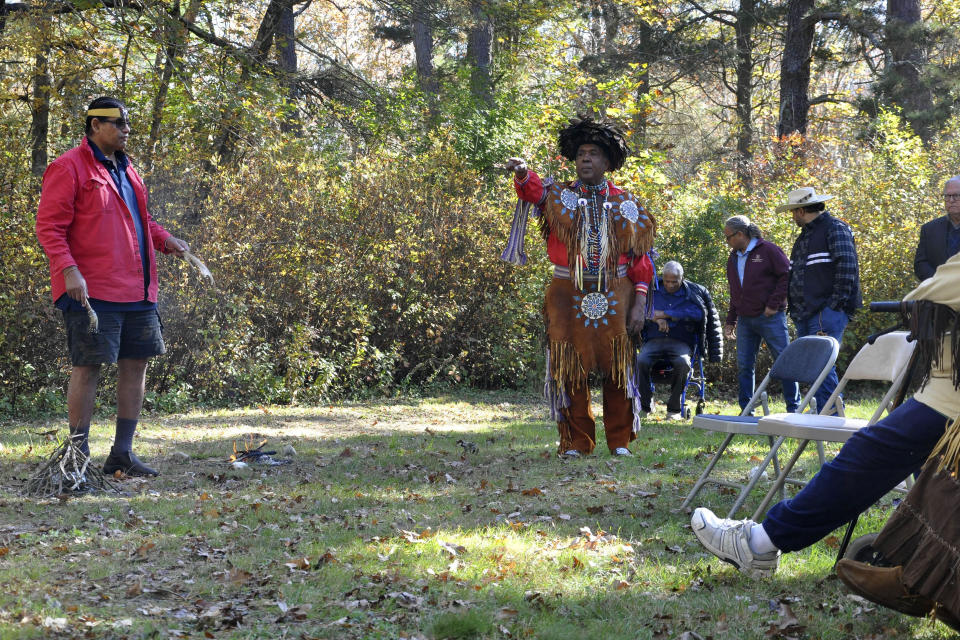 Narragansett Indian Tribe Medicine Man and Historic Preservation Officer John Brown, left, and Chief Sachem Anthony Dean Stanton, right, participate in a ceremony, Saturday, Oct. 23, 2021, in a wooded area, in South Kingstown, R.I., on land they believe to be the site of the Great Swamp Massacre, The Public's Radio reported. The land where the Rhode Island Narragansett tribe survived near-annihilation in a battle with English colonists on Dec. 19, 1675, has been transferred to the tribe. The transfer of the land from the Rhode Island Historical Society was finalized Friday, Oct. 22. (Alex Nunes/The Public's Radio, WNPN 89.3FM via AP)