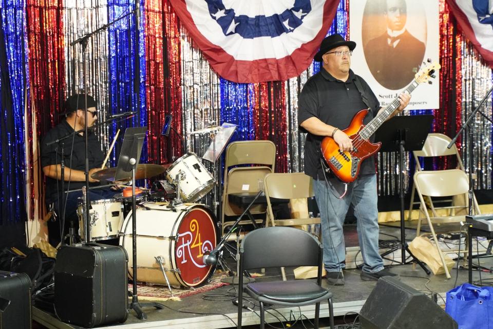 Two veteran members of the local band Los Hermanos, are pictured earlier this July performing in Adrian during the River Raisin Ragtime Revue on the campus of PlaneWave Instruments. Band members here are, from left, drummer Santos Villegas Jr. and Lawrence Pabolo on the bass guitar.