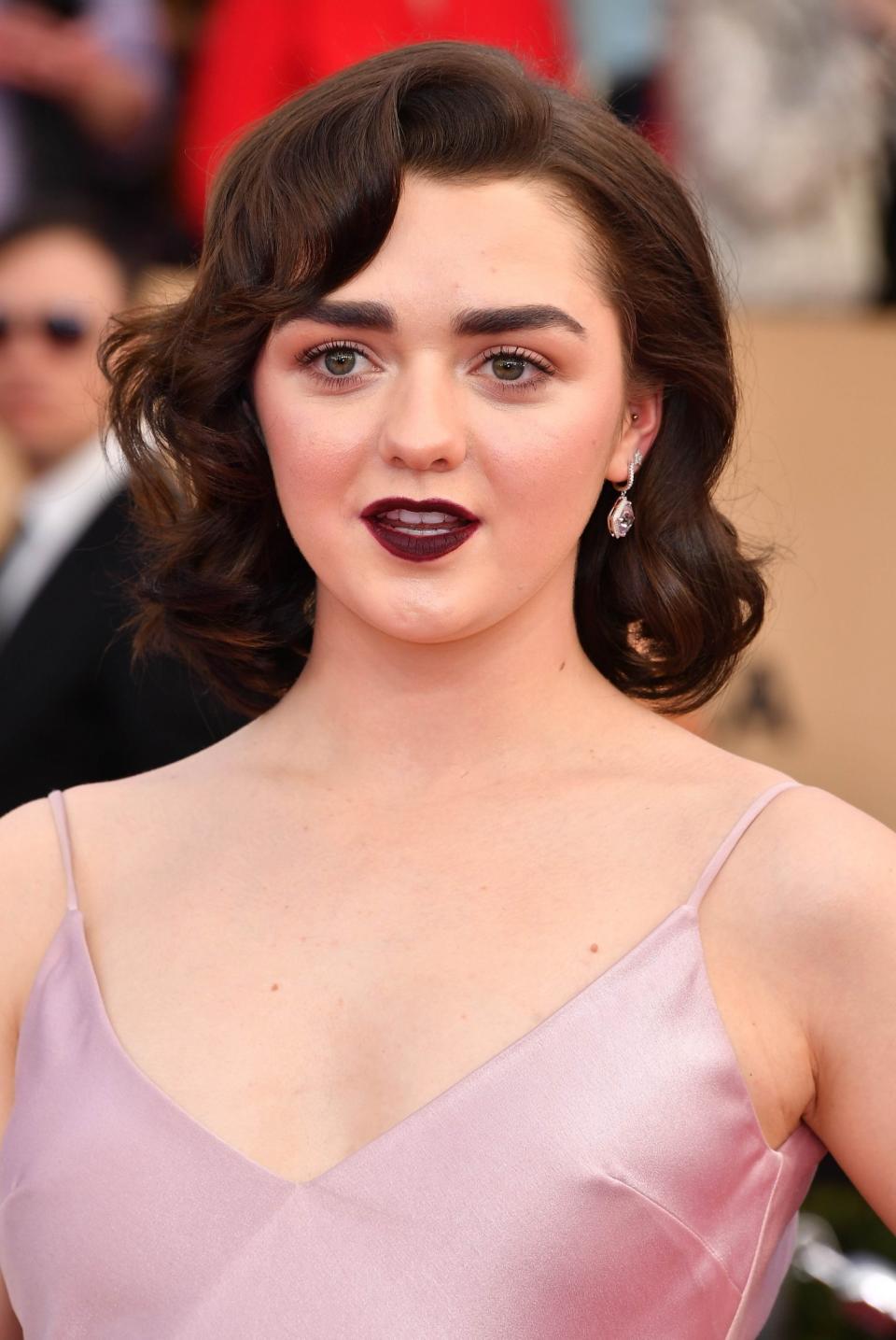 <p>Always one to put a slight edge on her red carpet outfits, Maisie Williams paired her girly pink dress with vampy hair and make-up. She did this effortlessly by modelling an oxblood lip and big retro curls. [Photo: Getty] </p>