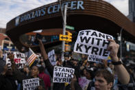 FILE - Protesters rallying against COVID-19 vaccination mandates and in support of basketball player Kyrie Irving gather in the street outside the Barclays Center before an NBA basketball game between the Brooklyn Nets and the Charlotte Hornets, Sunday, Oct. 24, 2021, in New York. From the NBA's Kyrie Irving missing the first months of the Brooklyn Nets' season before making a partial return, to the NFL's Aaron Rodgers going from revered veteran to polarizing figure, to a diplomatic standoff over tennis star Novak Djokovic's exemption to play in the Australian Open, sports figures have found themselves cheered and jeered as the most famous faces in fights over vaccine mandates and refusals. (AP Photo/John Minchillo, File)