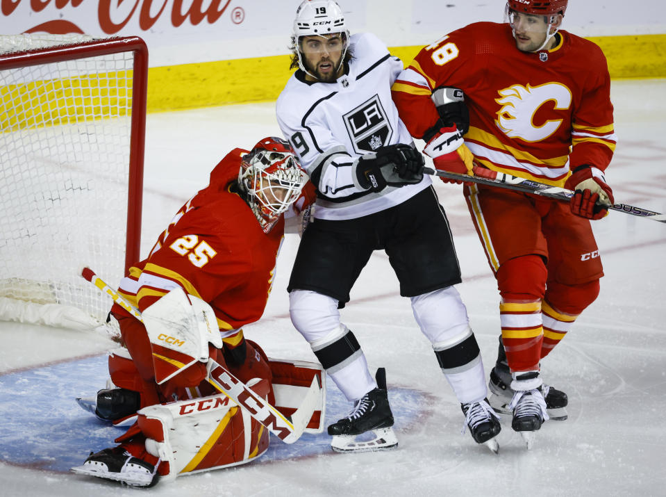 Los Angeles Kings forward Alex Iafallo, center, is checked by Calgary Flames defenseman Dennis Gilbert, right, into goalie Jacob Markstrom during the second period of an NHL hockey game Tuesday, March 28, 2023, in Calgary, Alberta. (Jeff McIntosh/The Canadian Press via AP)