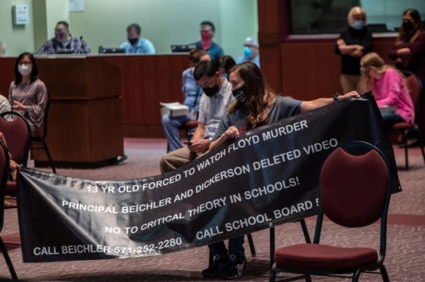 A woman holds a banner attacking critical race theory at a board meeting of Loudoun County Public Schools, Oct. 12. (Andrew Caballero-Reyonds / Getty Images)