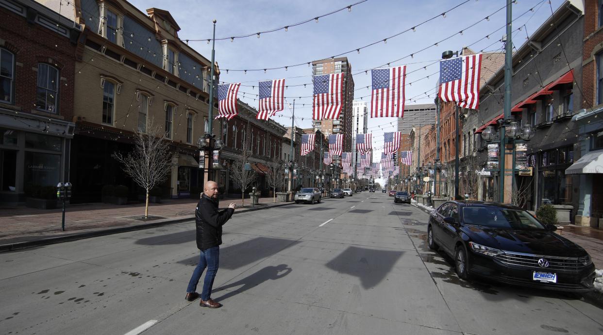 Charles Bevier of Denver stands in the center of normally-congested Larimer Street to take a photograph of the nearly-empty throughfare as residents deal with the spread of coronavirus on Saturday, March 21, 2020, in Denver.