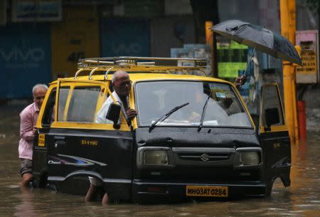 People push a taxi through a waterlogged street after heavy rains in Mumbai, July 8, 2018. REUTERS/Francis Mascarenhas