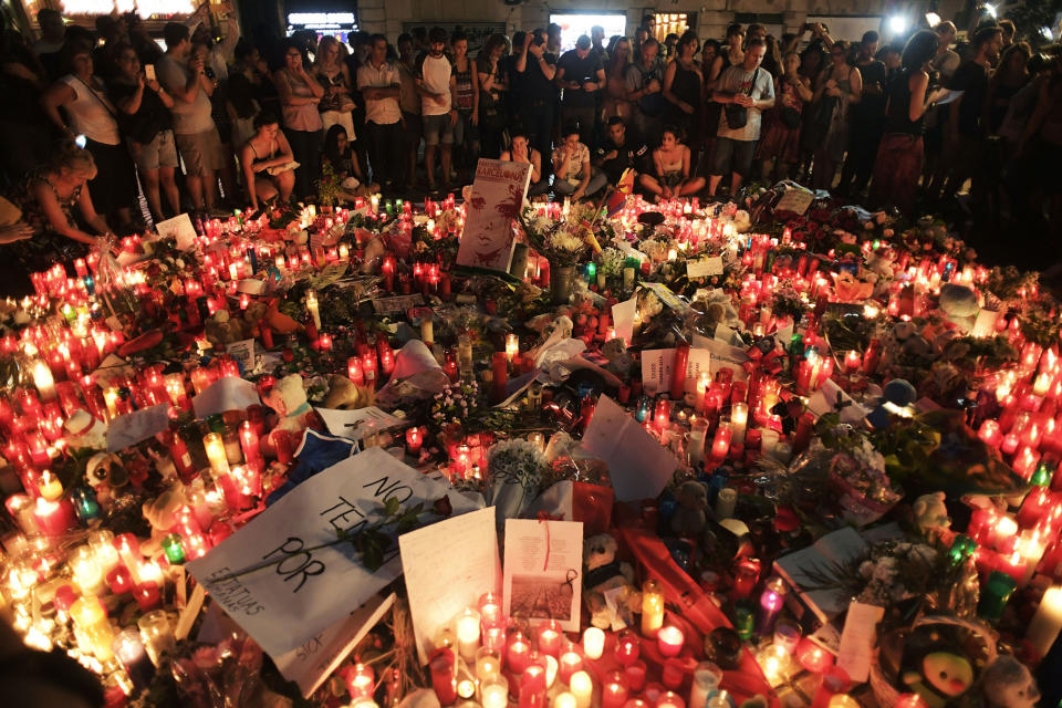 <p>AUG. 18, 2017 – People stand next to flowers, candles and other items set up on the Las Ramblas boulevard in Barcelona as they pay tribute to the victims of the Barcelona attack.<br> Drivers, on August 17, 2017 plowed into pedestrians in two quick-succession, separate attacks in Barcelona and another popular Spanish seaside city, leaving 14 people dead and injuring more than 100 others. Some eight hours later in Cambrils, a city 120 kilometres south of Barcelona, an Audi A3 car rammed into pedestrians, injuring six civilians and a police officer. (Photo: Javier Soriano/AFP/Getty Images) </p>