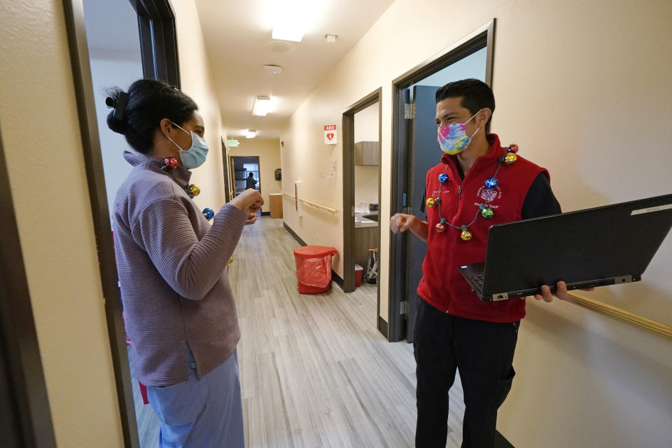 Dr. Cristina Toledo-Cornell, left, shares a socially distanced fist bump with Dr. Dakotah Lane after the first COVID-19 vaccination was given to a Lummi Nation tribal member Thursday, Dec. 17, 2020, on the Lummi Reservation, near Bellingham, Wash. The Native American tribe began rationing its first 300 doses of vaccine as it fights surging cases with a shelter-in-place order. (AP Photo/Elaine Thompson)