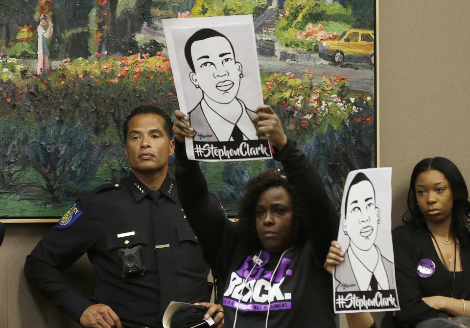 In this March 27, 2018, photo, drawings of police shooting victim Stephon Clark are held up next to Sacramento Police Chief Daniel Hahn, left, during a meeting of the Sacramento City Council held to discuss the shooting, in Sacramento, Calif. A wave of police killings of young black men in 2014 prompted 24 states to quickly pass some type of law enforcement reform, but many declined to address the most glaring issue: police use of force. Six years later, only about a third of states have passed laws on the question. (AP Photo/Rich Pedroncelli)
