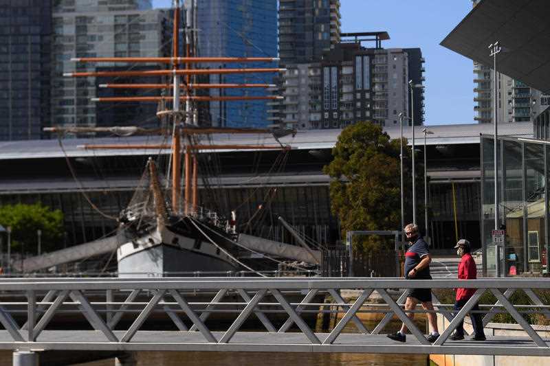 Two people walk in Melbourne wearing face masks.