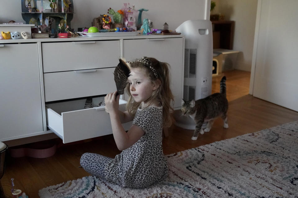 Aylah Levy, 6, holds up a feather she found next to her cat, Mia, in Albany, Calif., Wednesday, Nov. 8, 2023. (AP Photo/Jeff Chiu)