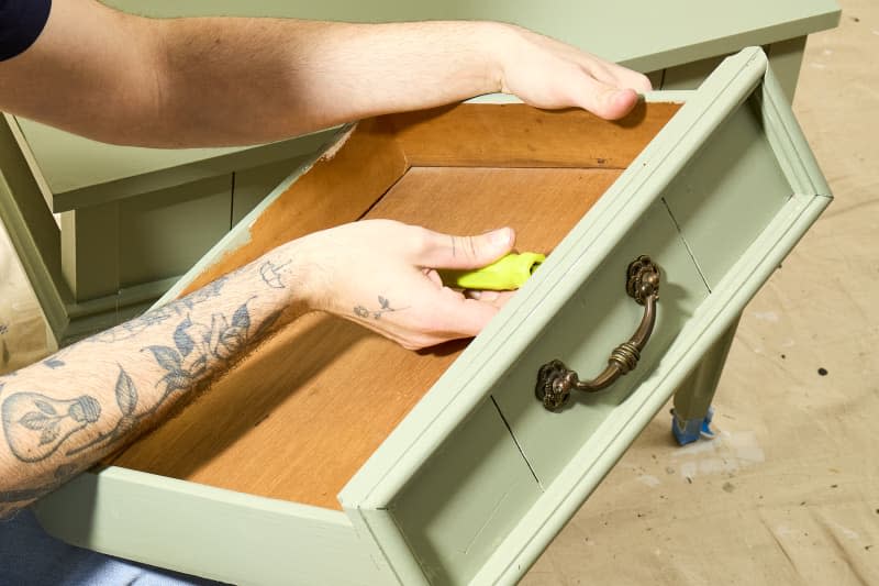 angled shot of the hardware being put back onto the painted drawer.