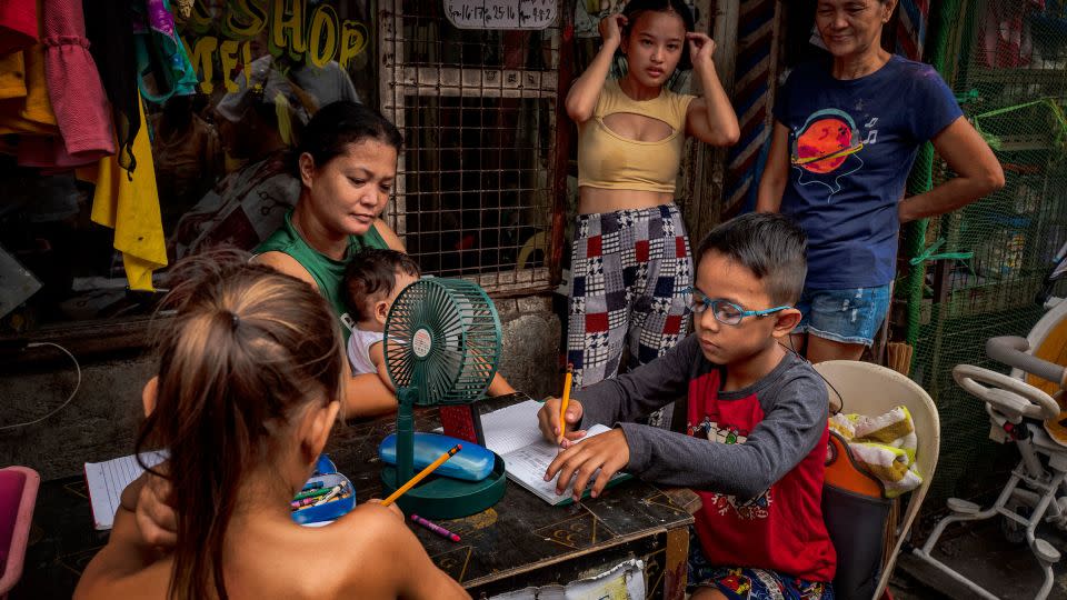 Children huddle around a small desk and mini-fan to take classes remotely as schools were shut amid extreme heat in Tondo district in Manila, Philippines on May 03, 2024. The heat index shot up to 53 degrees Celsius in some parts of the country. - Ezra Acayan/Getty Images