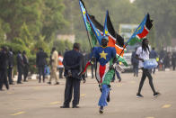 A man runs with flags next to the audience as they await the arrival of Pope Francis for a Holy Mass at the John Garang Mausoleum in Juba, South Sudan Sunday, Feb. 5, 2023. Pope Francis is in South Sudan on the final day of a six-day trip that started in Congo, hoping to bring comfort and encouragement to two countries that have been riven by poverty, conflicts and what he calls a "colonialist mentality" that has exploited Africa for centuries. (AP Photo/Ben Curtis)