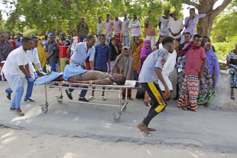 A civilian who was wounded in suicide car bomb attack is helped to be taken to hospital in Mogadishu, Somalia, Saturday, Dec. 28, 2019. A police officer says a car bomb has detonated at a security checkpoint during the morning rush hour in Somalia's capital. (AP Photo/Farah Abdi Warsame)