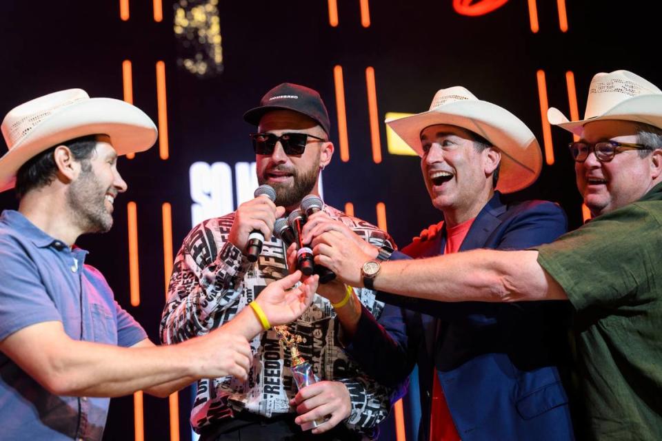 Big Slick hosts (all in white cowboy hats) Paul Rudd, left, Rob Riggle and Eric Stonestreet offer their mics to Kansas City Chiefs tight end Travis Kelce during the Big Slick Celebrity Weekend auction in June at the T-Mobile Center.