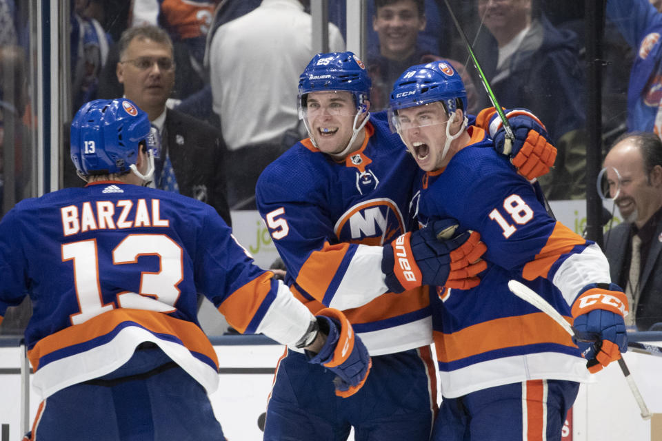 New York Islanders left wing Anthony Beauvillier (18) celebrates his game-winning overtime goal against the Buffalo Sabres with teammates Mathew Barzal (13) and Devon Toews, center, in an NHL hockey game, Saturday, Dec. 14, 2019 in Uniondale, N.Y. The Islanders won 3-2. (AP Photo/Mark Lennihan)