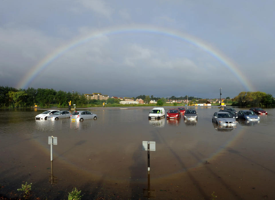 A rainbow reflects in surface water which covered a car park in Weymouth, Dorset.
