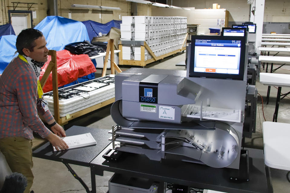 Allegheny County Election Division Deputy Manager Chet Harhut demonstrates a mail-in and absentee ballot counting machine at the Elections warehouse in Pittsburgh Monday, June 1, 2020. Pennsylvania holds its primary on Tuesday, June 2. (AP Photo/Gene J. Puskar)