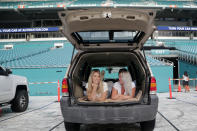 Amanda Scherner, left, and Rachel Anhalt sit in their vehicle to watch a movie as part of the Outdoor Theater program offered by the Miami Dolphins at the Hard Rock Stadium amid the new coronavirus pandemic, Thursday, June 18, 2020, in Miami Gardens, Fla. The outdoor theater program offers a safe way for residents to safely get out of their homes and remain socially distant. (AP Photo/Lynne Sladky)