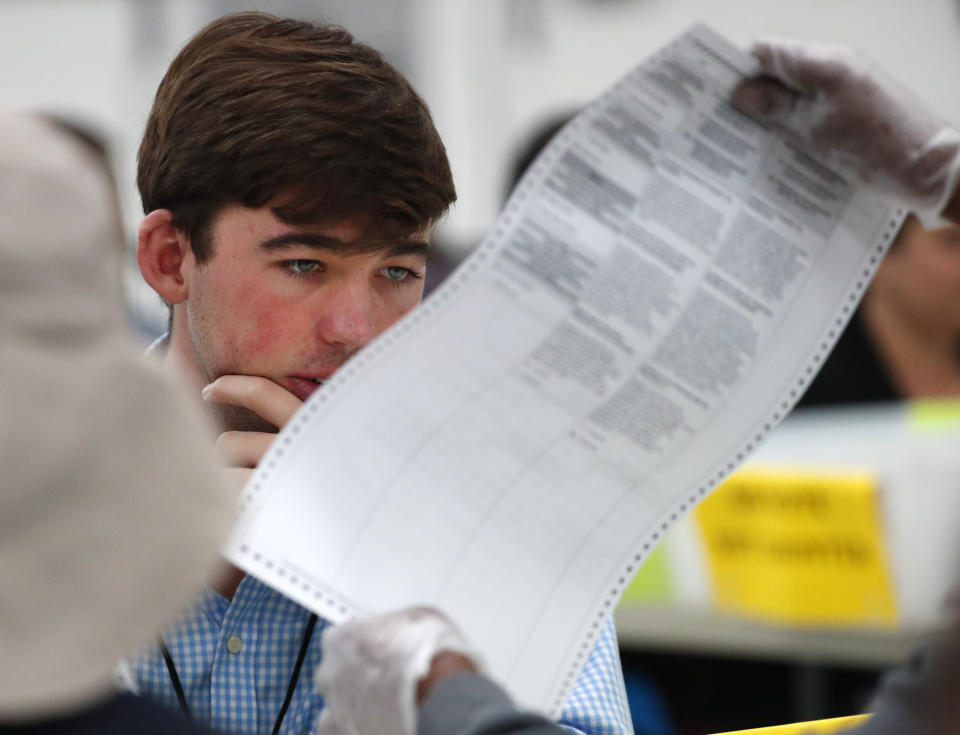 FILE- In this Friday, Nov. 16, 2018, file photo a Republican observer looks at a ballot during a hand recount at the Broward County Supervisor of Elections office in Lauderhill, Fla. Florida Republican Gov. Rick Scott is leading incumbent Sen. Bill Nelson in the state’s contentious Senate race. Official results posted by the state on Sunday, Nov. 18, showed Scott ahead of Nelson following legally-required hand and machine recounts. State officials will certify the final totals on Tuesday. (AP Photo/Wilfredo Lee, File)