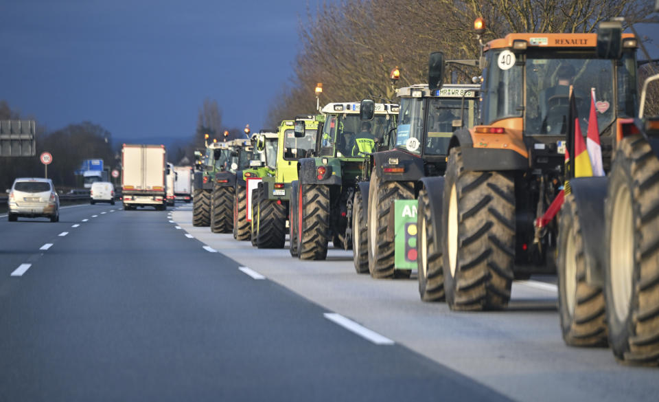 Farmers drive in convoy with their tractors on the A66 highway near Wiesbaden, Germany, Monday, Jan. 8, 2024. Farmers are blocking highway access roads in parts of Germany and gathering for demonstrations, launching a week of protests against a government plan to scrap tax breaks on diesel used in agriculture. (Arne Dedert/dpa via AP)