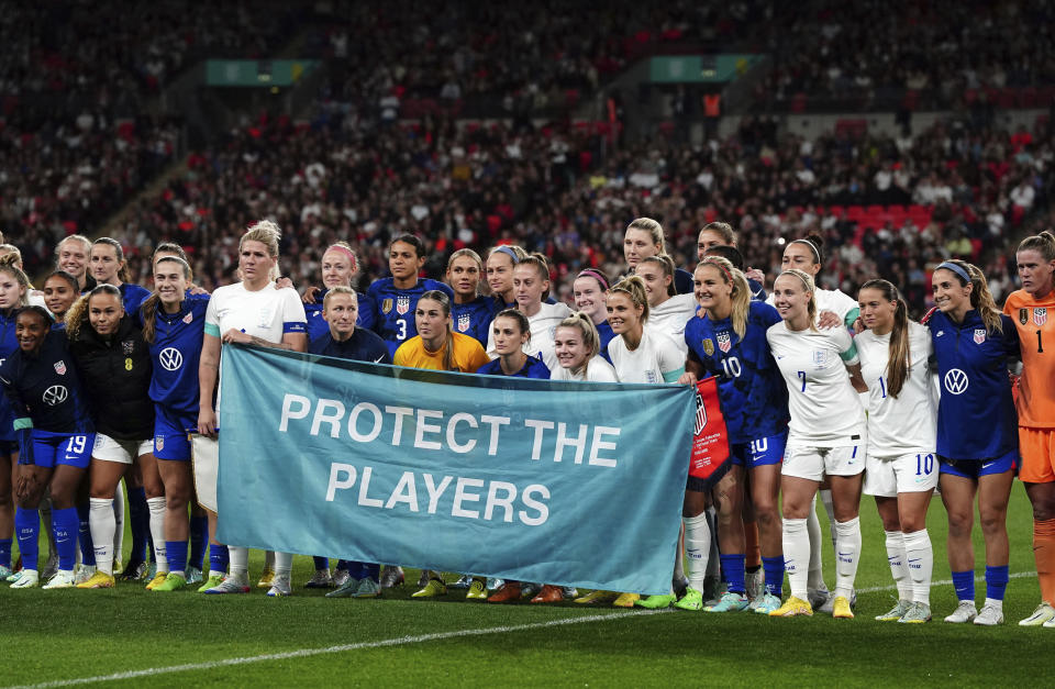 England and US teams stand together with a banner as a show of solidarity for victims of abuse before the women's friendly soccer match between England and the US at Wembley stadium in London, Friday, Oct. 7, 2022. (Nick Potts/PA via AP)