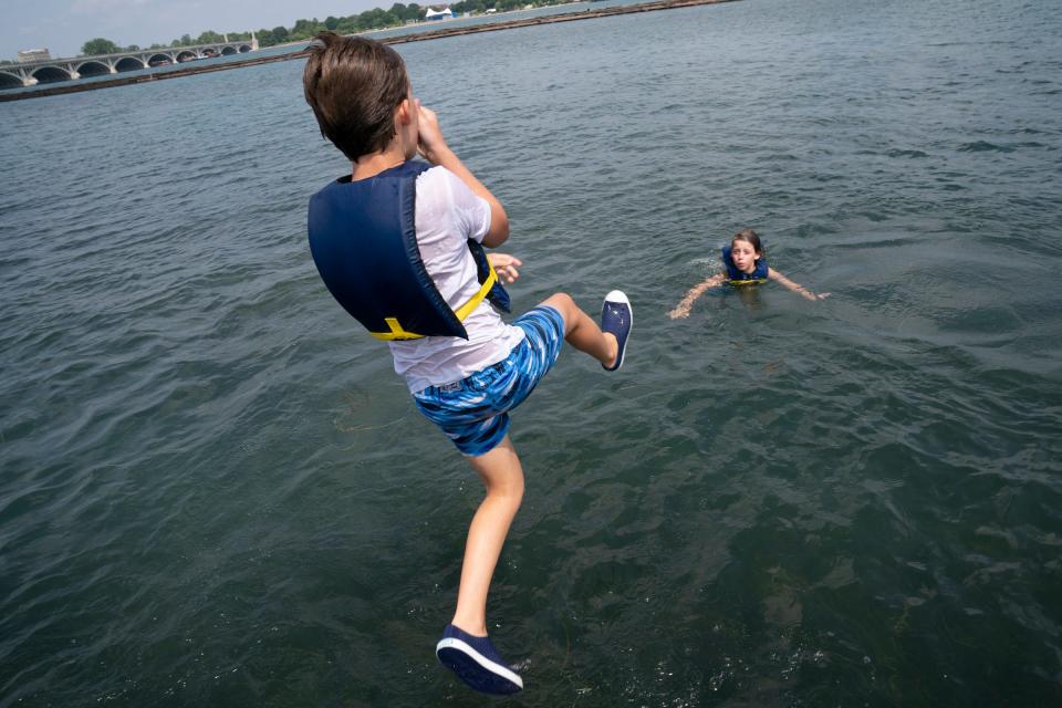 Erik Groeneveld, 11, of Bloomfield Hills, left, takes a dip as one of his triplet brothers, Arie Groeneveld, 11, floats in the Detroit River after a hot day of sailing with the Challenge the Wind program on Thursday, July 20, 2023, from the banks of the Belle Isle Boat House.