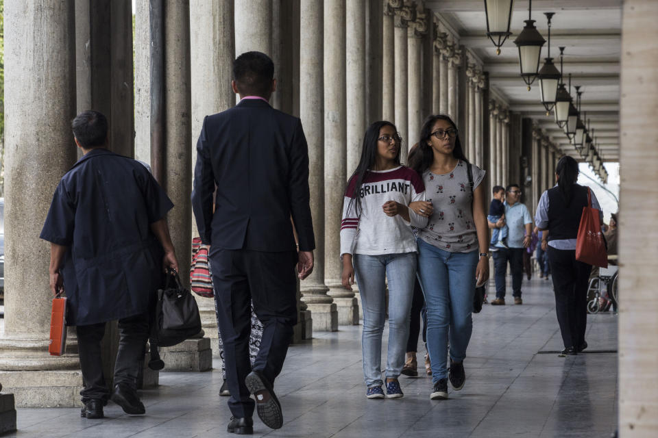People walk through the galleries of shops at the central park in Guatemala City, Friday, July 26, 2019. The Trump administration signed an agreement with Guatemala Friday that will restrict asylum applications to the U.S. from Central America. (AP Photo/ Oliver de Ros)