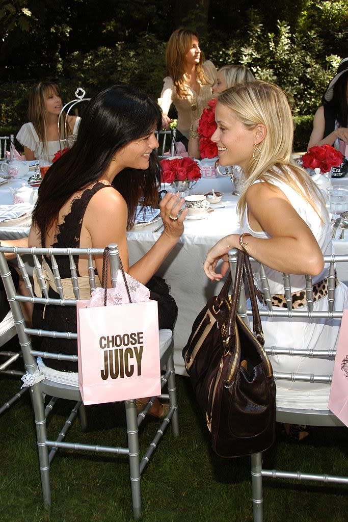 selma and reese are sitting and chatting with a juicy bag on their chair