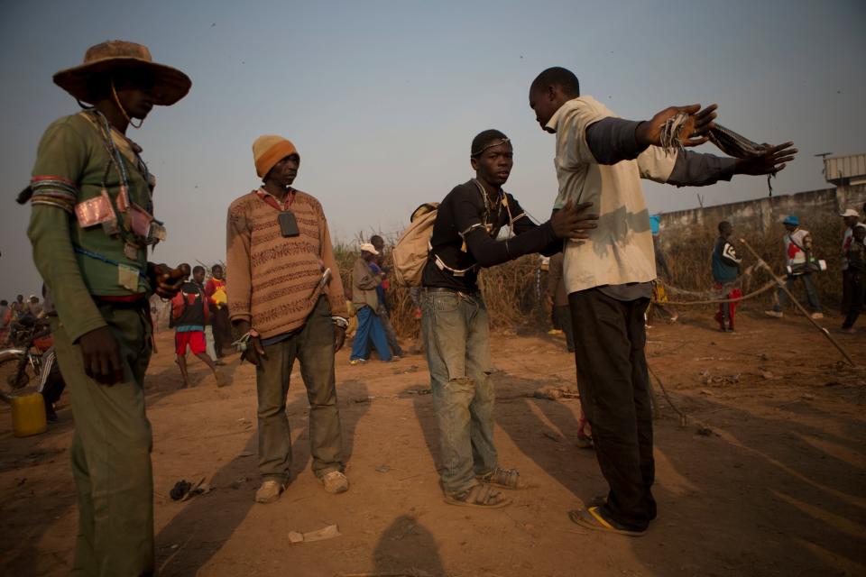 Anti-balaka militiamen frisk men for weapons at an entrance to an informal camp housing an estimated 100,000 displaced people, at Mpoko Airport in Bangui, Central African Republic, Wednesday, Jan. 8, 2014. Food and supplies distribution by the World Food Program and the United Nations Refugee Agency began Tuesday and was expected to last 10 days. It is the first aid delivery to reach the camp since Dec. 15, and many families were lacking food or even rudimentary shelter from the harsh daytime sun and chilly nights. Residents were receiving supplies including rice, cooking oil, tarps, mats, and blankets. (AP Photo/Rebecca Blackwell)