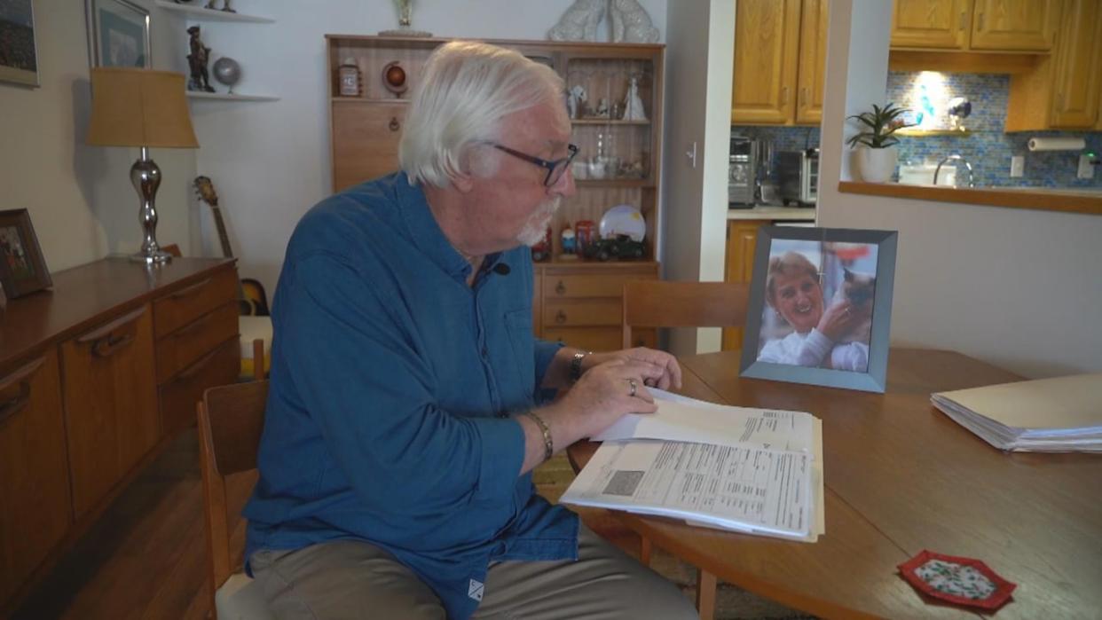 Malcolm Roberts looks over documents at his home in Kelowna, B.C., on Wednesday. His wife, Eleanor, died in 2021, changing his income and tax situation.   (Brady Strachan/CBC - image credit)