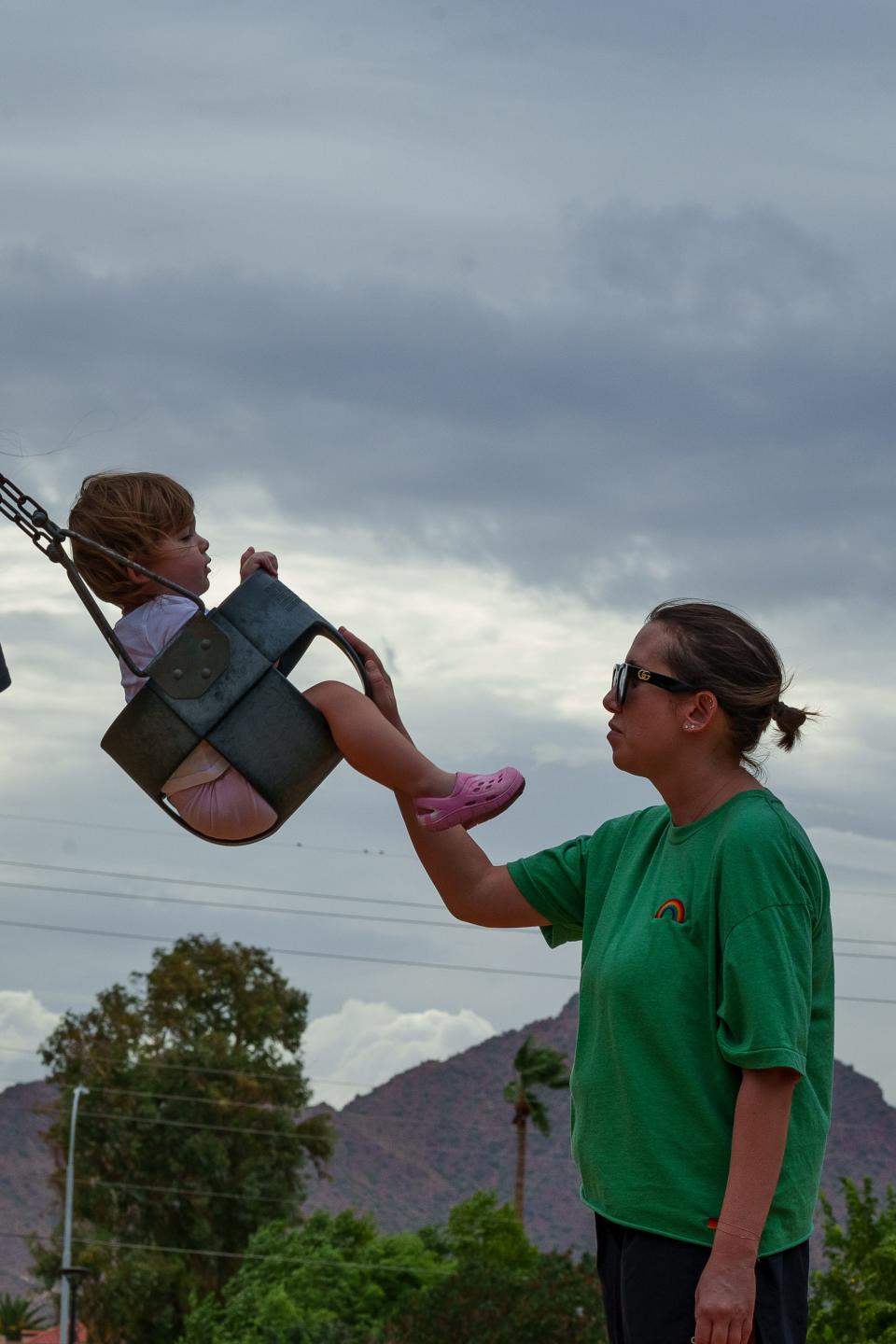 Grace Montgomery pushes daughter, Evie Montgomery on the swings in the stormy weather at Chaparral Park in Scottsdale, Ariz. as Tropical storm Hillary moves through Southern California on Aug. 20, 2023.