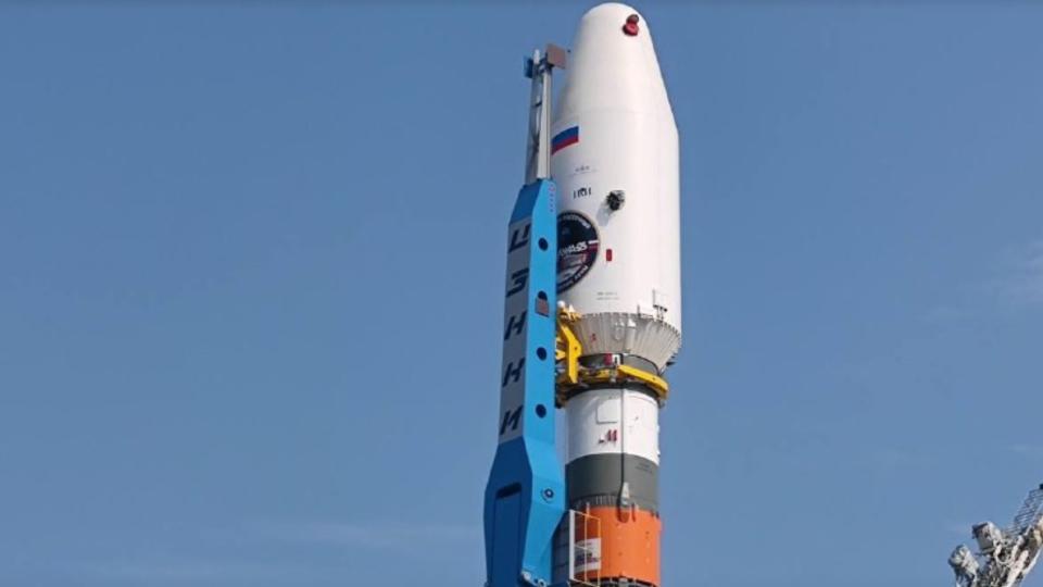 A white payload fairing sits atop a white, orange and green rocket.