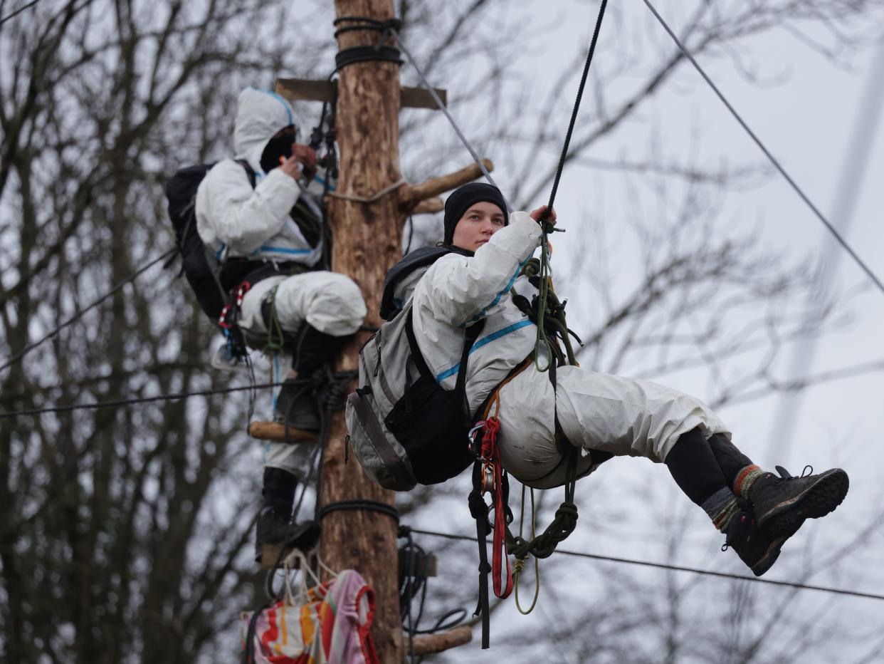 ERKELENZ, GERMANY - JANUARY 13: An activist stands on a pole high above the ground as another hangs on a rope fastened between poles as police close in at the settlement of Luetzerath on January 13, 2023 near Erkelenz, Germany. Police are evicting environmental activists who have occupied the abandoned Luetzerath settlement and who are seeking to prevent Luetzerath's demolition that will make way for an expansion of the adjacent Garzweiler II open cast coal mine.Of the several hundred activists on site approximately a few dozen remain, some in treehouses and others attached to tall poles. The North Rhine-Westphalia state government of German Christian Democrats (CDU) and Greens has approved the demolition and the coal mine expansion, while at the same time announcing an accelerated phase out of coal-fired energy production in the state from 2028 to 2030. Other nearby settlements that were also slated for demolition will now be spared, though critics point out that Germany has sufficient energy production capacity and does not need the coal lying beneath Luetzerath. (Photo by Sean Gallup/Getty Images)