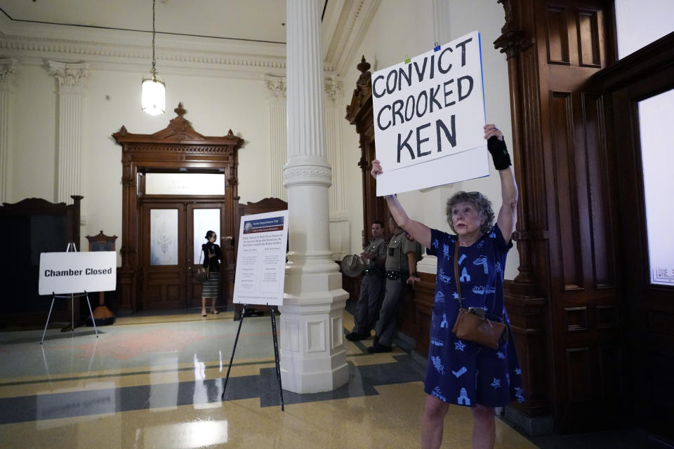 Ellen McCluskey holds a sign outside the Senate Chamber as the impeachment trial for suspended Texas Attorney General Ken Paxton continues at the Texas Capitol, Thursday, Sept. 14, 2023, in Austin, Texas. (AP Photo/Eric Gay)