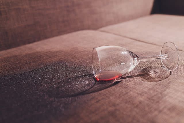 <p>Getty</p> Red wine spilled on a brown couch sofa in a stock photo