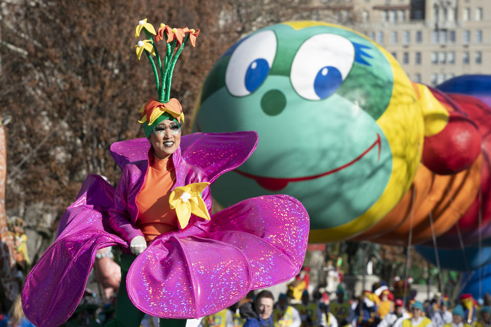 A woman in a flower costume marches in front of the Wiggle Worm balloon during the Macy's Thanksgiving Day Parade, Thursday, Nov. 28, 2019, in New York. (AP Photo/Mark Lennihan)