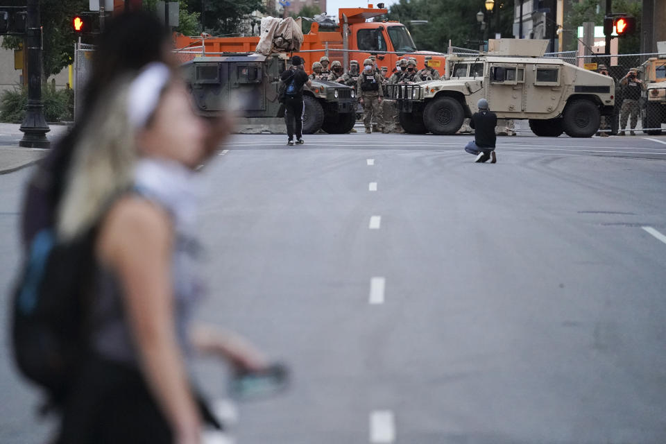 Members of the Kentucky National Guard watch people in the street, Thursday, Sept. 24, 2020, in Louisville, Ky. Authorities pleaded for calm while activists vowed to fight on Thursday in Kentucky's largest city, where a gunman wounded two police officers during anguished protests following the decision not to charge officers for killing Breonna Taylor. (AP Photo/John Minchillo)