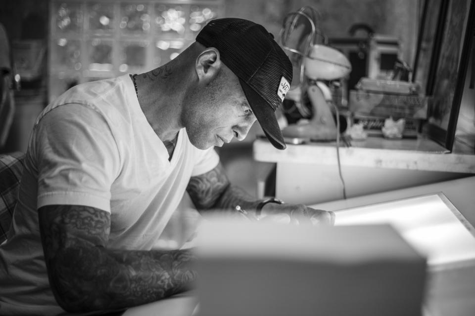 Ami James sketching at his tattoo studio. Photo: Tattoodo