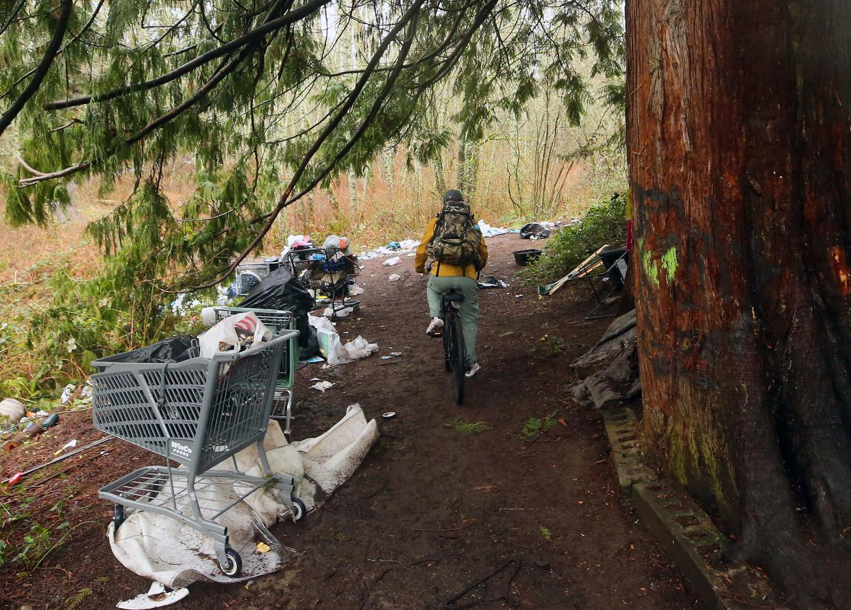 An encampment resident rides their bike out of the Hospital Hill area of the Clear Creek Trail in Silverdale on Wednesday Feb. 28, 2024.