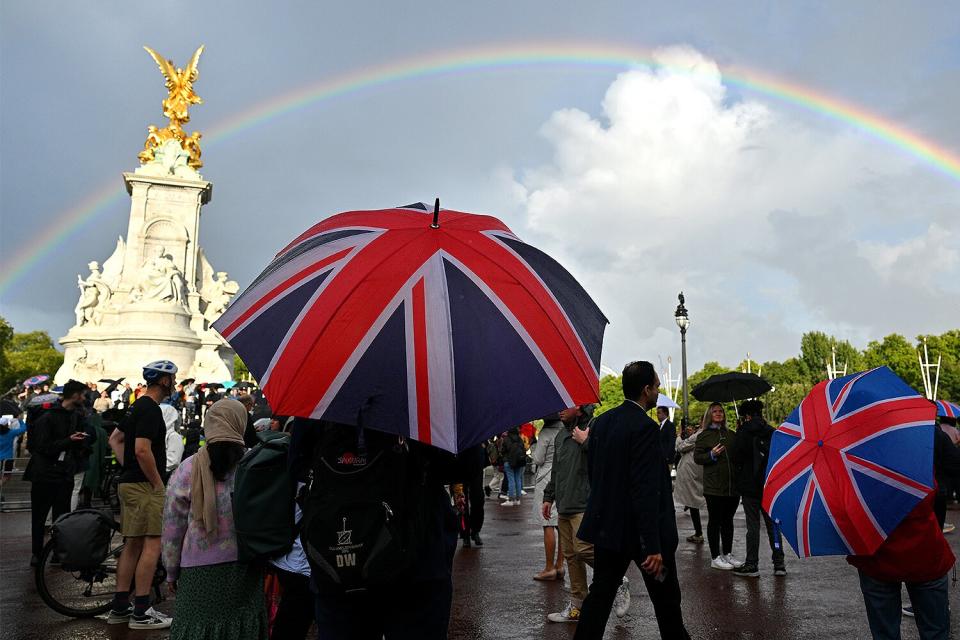 A man looks on holding a Union flag umbrella as a rainbow is seen outside of Buckingham Palace on September 08, 2022 in London, England. Buckingham Palace issued a statement earlier today saying that Queen Elizabeth was placed under medical supervision due to concerns about her health.