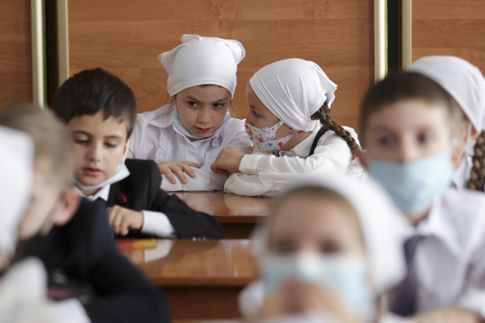 Pupils wearing face masks to protect against coronavirus sit in a classroom during a ceremony marking the start of classes at a school as part of the traditional opening of the school year known as "Day of Knowledge" in Grozny, Russia, Tuesday, Sept. 1, 2020. Across the country, schools start their usually festive opening day on Sept. 1. (AP Photo/Musa Sadulayev)