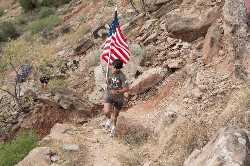 A young runner leads his team up the trail with a flag Saturday morning at the Iwo Jima Flag Run at Palo Duro Canyon.