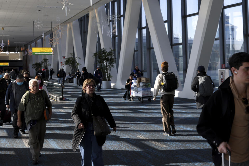 Travelers walk through LaGuardia Airport's Terminal B, Tuesday, Nov. 22, 2022, in New York. Travel experts say the ability of many people to work remotely is letting them take off early for Thanksgiving or return home later. Crowds are expected to rival those of 2019, the last Thanksgiving before the pandemic. (AP Photo/Julia Nikhinson)