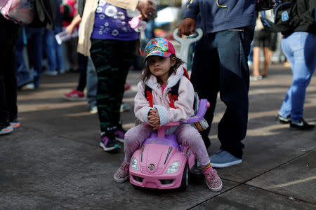 A girl waits with her parents before departing with a caravan of migrants from El Salvador en route to the United States, in San Salvador, El Salvador, October 28, 2018. REUTERS/Jose Cabezas