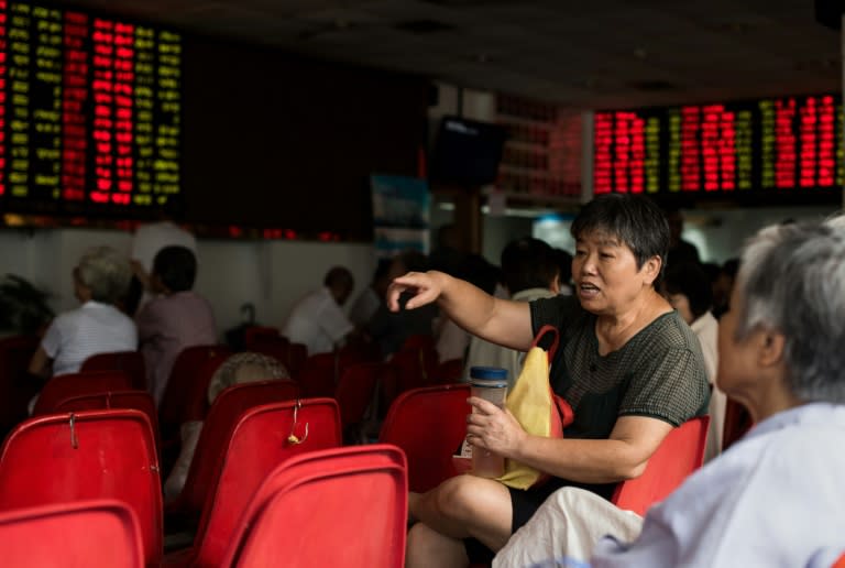 Investors monitor screens showing stock market movements at a brokerage house in Shanghai on August 13, 2015