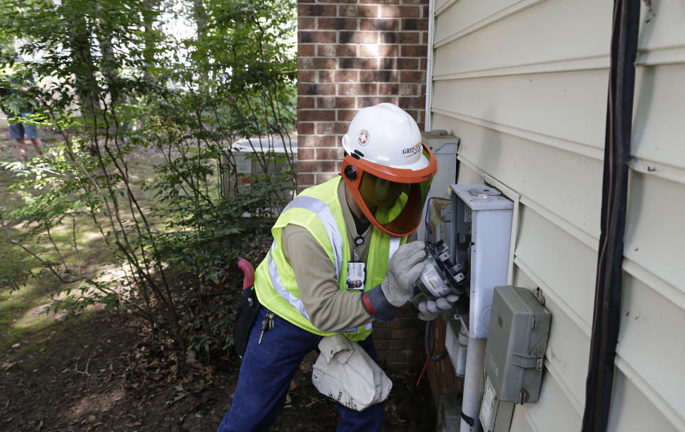 In this photo taken Friday, July 13, 2018 Grid One Solutions employee Spencer Powell removes an older electric meter to install a new smart meter for Duke Energy Progress at a residence in Raleigh, N.C.  Electric utilities are pouring billions of dollars into a race to prevent terrorists or enemy governments from shutting down the power grid while also making the delivery system ready for a world with much more renewable energy. Utilities have long based their business on building power plants and selling the juice to customers to pay for it all. With energy conservation making big new plants less necessary, utilities are banking on future profits from updating the power grid. (AP Photo/Gerry Broome)