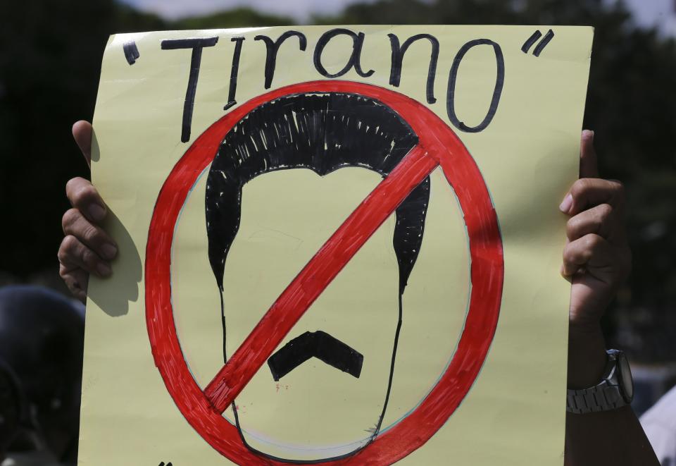 An opposition member holds a sign with the likeness of Venezuela's President Nicolas Maduro with text that reads in Spanish "Tyrant" during a protest in Caracas, Venezuela, Friday, Jan. 11, 2019. The head of Venezuela's opposition-run congress says that with the nation's backing he's ready to take on Nicolas Maduro's presidential powers and call new elections.(AP Photo/Fernando Llano)