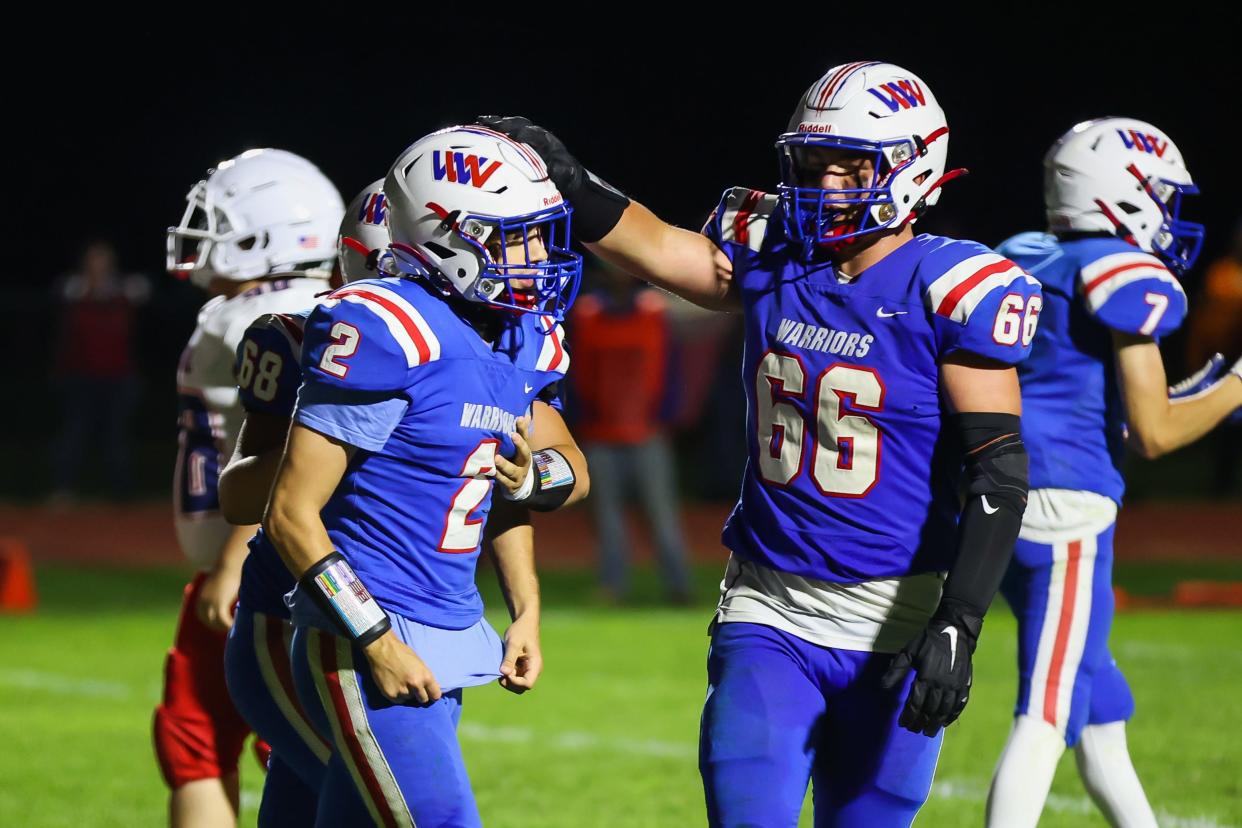 Winnacunnet's DJ Sciacca is congratulated by teammates Anthony Magri (68) and Owen Denio (66) after Sciacca scored a touchdown in the fourth quarter of Friday's Division I football game. It was the first touchdown of the season for the Warriors.