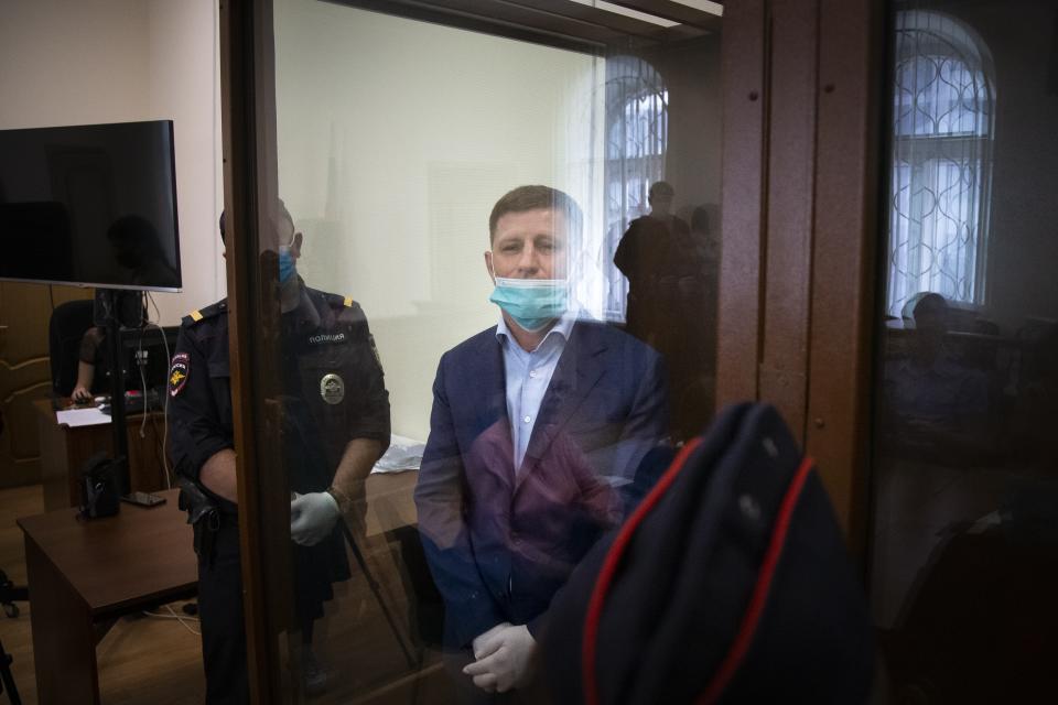 A governor of the Khabarovsk region along the border with China, Sergei Furgal, center, stands prior to a session in a courtroom in Moscow, Russia, Friday, July 10, 2020. A provincial governor in Russia's far east has been arrested on charges of involvement in multiple murders and was flown to Moscow. The court ordered Frugal to be jailed for two months as the investigation continues. (AP Photo/Alexander Zemlianichenko)