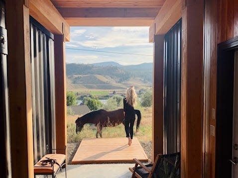 Cathi Marshall and her horse standing outside of her shipping container house looking out onto the mountains